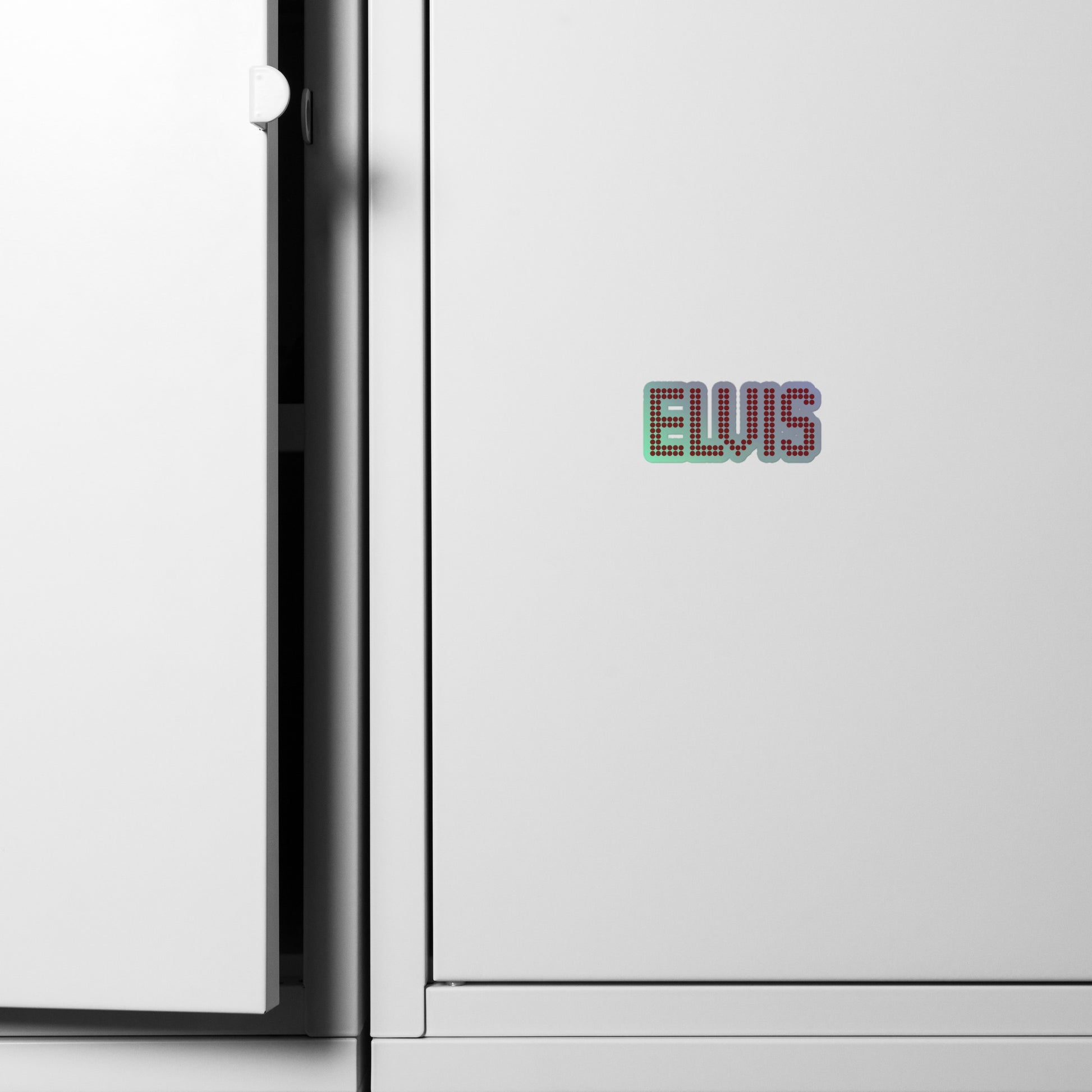 A close-up of a white cabinet with a small colorful 'ELVIS' text decal on the front, next to the open door hinge.